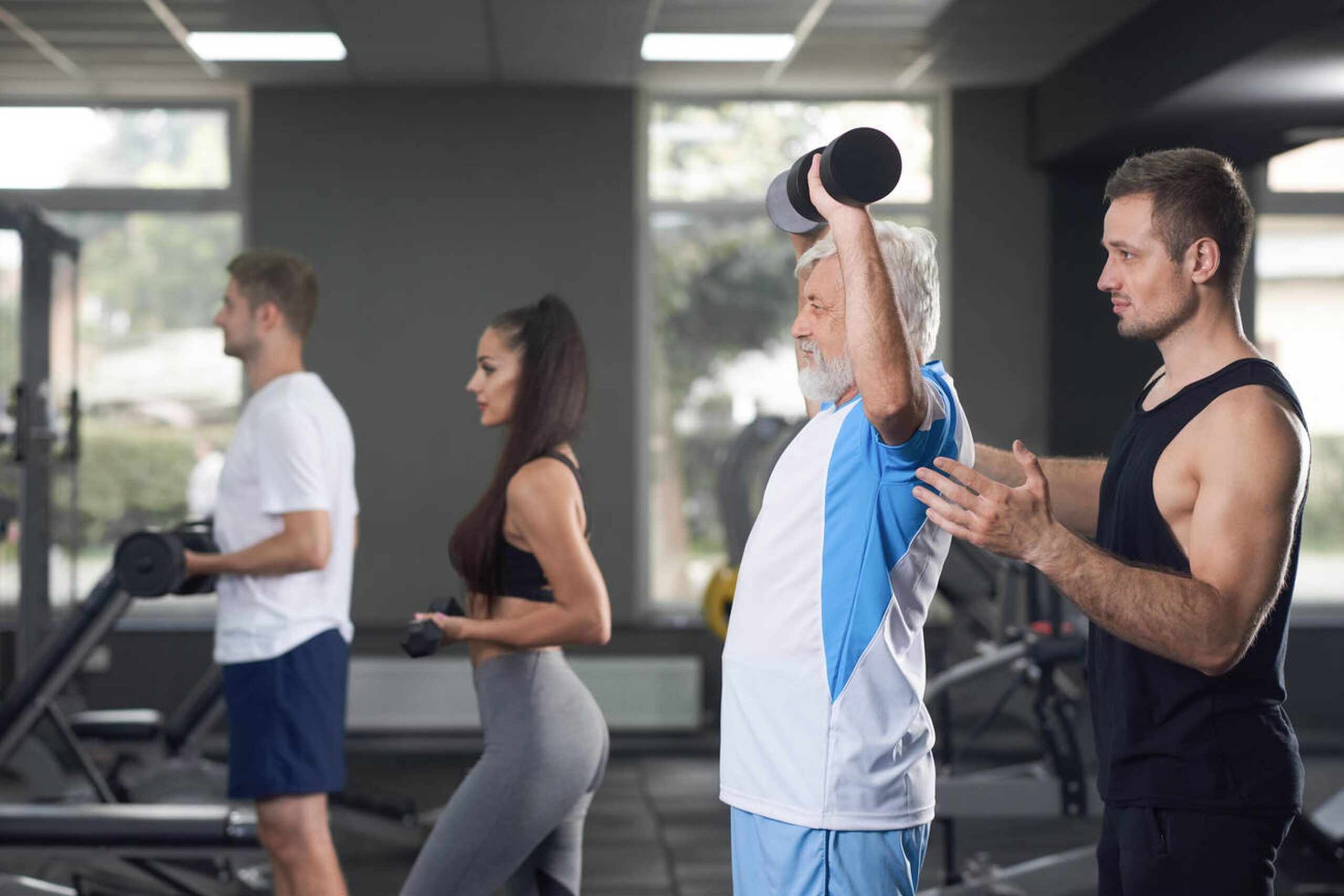 An active senior man smiling and lifting light weights, demonstrating how to improve bone density through exercise.